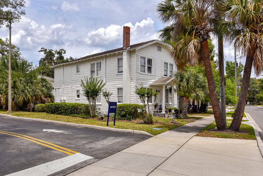 The corner building on the Annie Street assemblage under live oaks.