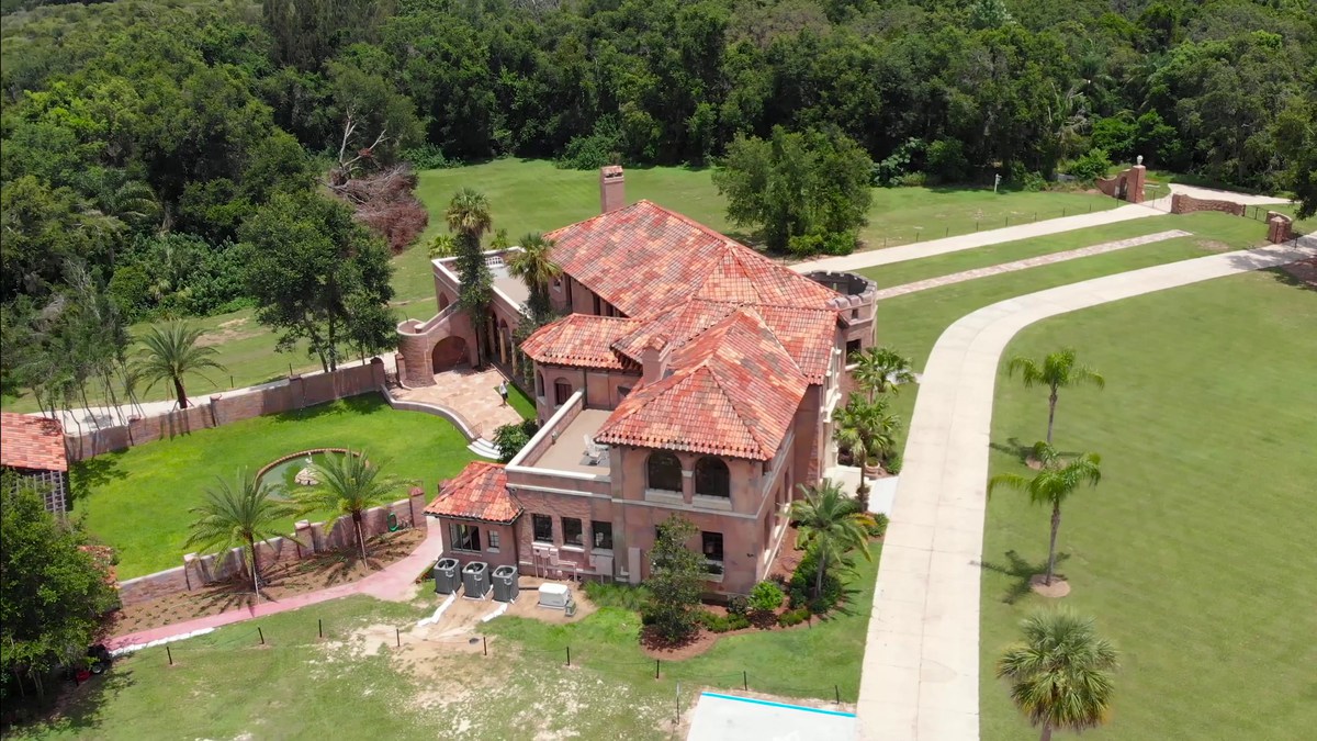 The Howey Mansion from the air, its tiled roofs and walled courtyard set in lawn and palms.