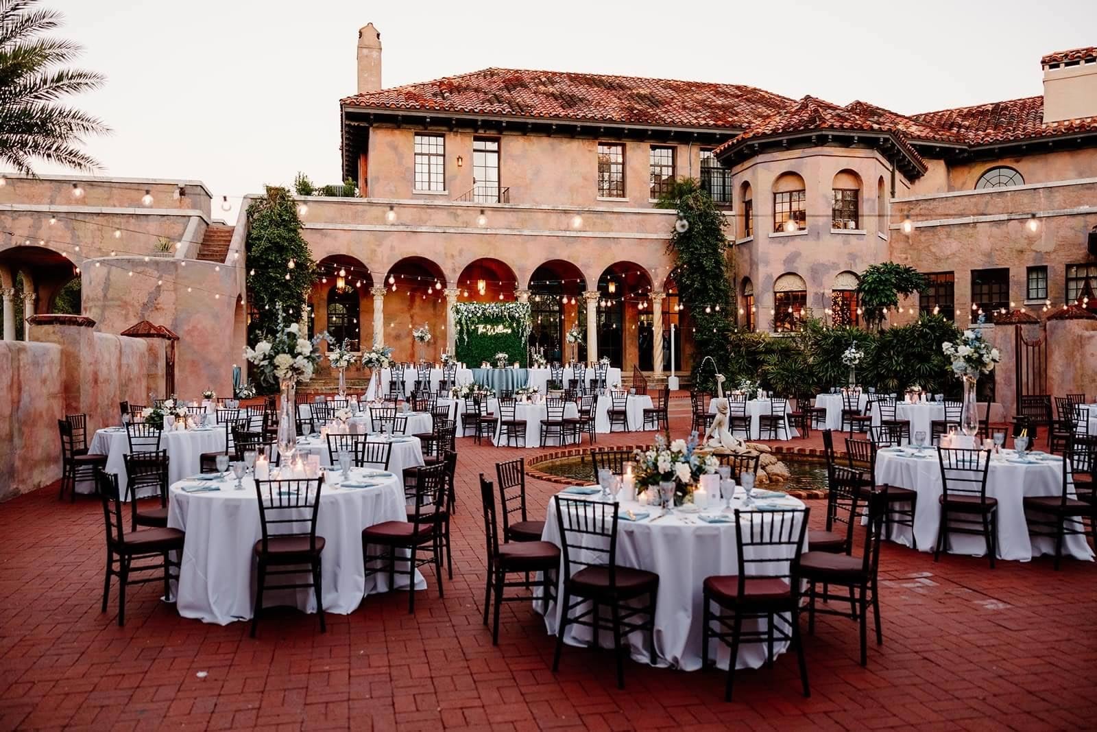The Howey Mansion courtyard at dusk, tables set around the fountain under festoon lights.