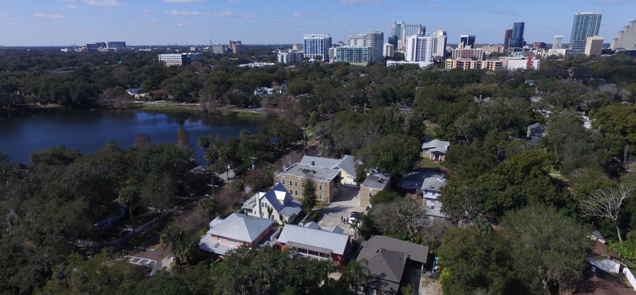Aerial over the Thornton Park assemblage in downtown Orlando, the lake to one side and the skyline behind.